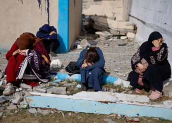 People rest next to damaged buildings, as Palestinian arrive in Rafah after they were evacuated from Nasser hospital in Khan Younis due to the Israeli ground operation, amid the ongoing conflict between Israel and Hamas, in the southern Gaza Strip, February 15, 2024. REUTERS/Mohammed Salem