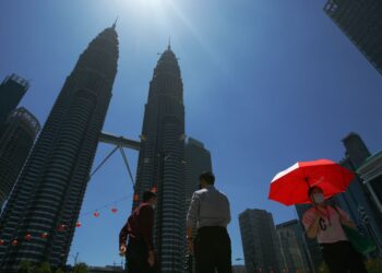 Pedestrian is seen using the umbrella in Jalan Ampang during hot weather and dry session on Feb 26. —AZMAN GHANI/The Star