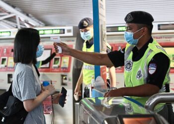 A Prasarana officer checking a passenger's temperature before they are allowed to enter the station in Kuala Lumpur.
