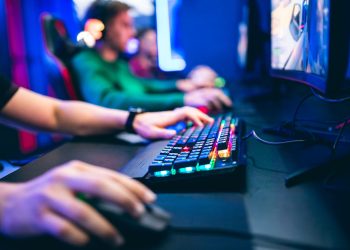Professional cyber video gamer studio room with personal computer armchair, keyboard for stream in neon color blur background. Soft focus.