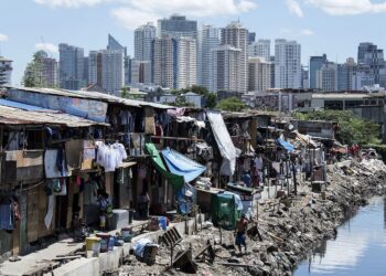 TOPSHOT - People living in a settlement walk about, as the skyline of Manila's financial district is seen in the background, on August 17, 2017. 
The Philippine economy grew by 6.5 percent in the three months to June, likely one of the fastest in Asia, the government said on August 17, defying concerns over President Rodrigo Duterte's unconventional leadership. / AFP PHOTO / Noel CELIS        (Photo credit should read NOEL CELIS/AFP/Getty Images)