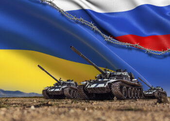 A Group of tanks lined up in front of Russian and Ukrainian flags. Several military army war battle tank vehicles on the terrain are ready to attack. Russian-Ukrainian conflict or war