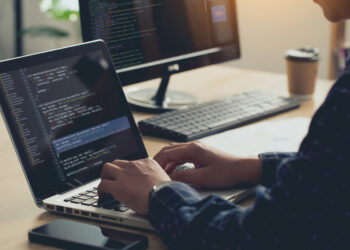 Professional Development programmer typing on a laptop Computer Keyboard. Screens Show Coding Language User Interface. Program Development, software, and coding technology, artificial chat, Website design.