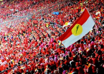 A member of Malaysia's opposition party United Malays National Organization's (UMNO) walks in front of UMNO logo during UMNO General Assembly in Kuala Lumpur, Malaysia, Sunday, Sept. 30, 2018. Malaysia's once ruling Malay party UMNO seeks to chart its future direction at its annual general meeting after its shocking ouster in May's general election. The UMNO leads a coalition that had broken up after many of its member parties left following the election loss. (AP Photo/Yam G-Jun)