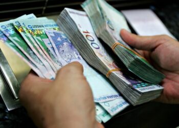 A customer counts ringgit bills in denominations of 1, 50 and 100 at the service window of a money changer in Kuala Lumpur, 22 July 2005. The Malaysian ringgit was appreciating gradually in cautious trade 22 July after the Malaysian central bank responded to China's yuan revaluation by scrapping the dollar peg in favour of a managed float. AFP PHOTO/TENGKU BAHAR