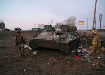 Ukrainian servicemen are seen next to a destroyed armoured vehicle, which they said belongs to the Russian army, outside Kharkiv, Ukraine February 24, 2022. REUTERS/Maksim Levin     TPX IMAGES OF THE DAY