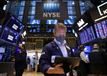 FILE PHOTO: A trader in a face mask works on the trading floor at the New York Stock Exchange (NYSE) as the Omicron coronavirus variant continues to spread in Manhattan, New York City, U.S., December 20, 2021. REUTERS/Andrew Kelly